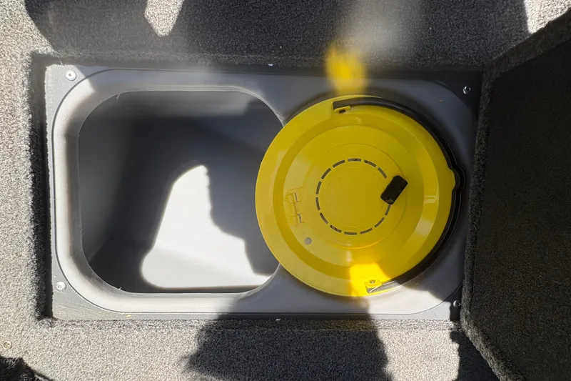 Slide: The Image of 2018 Tracker Targa V-18 Combo storage compartment with yellow lid, carpeted interior. - 24