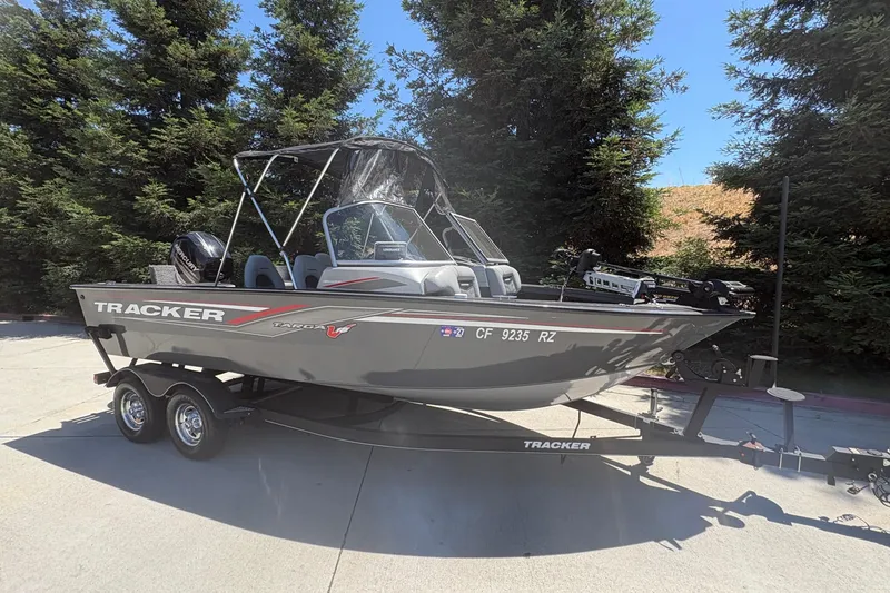 Slide: The Image of 2018 Tracker Targa V-18 Combo boat on trailer, parked outdoors with trees in background. - 3