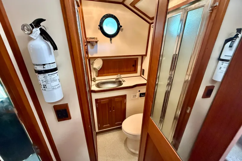 Slide: The Image of Bathroom interior of a 2000 Nordic Tug 37, featuring a sink, toilet, and fire extinguisher. - 49
