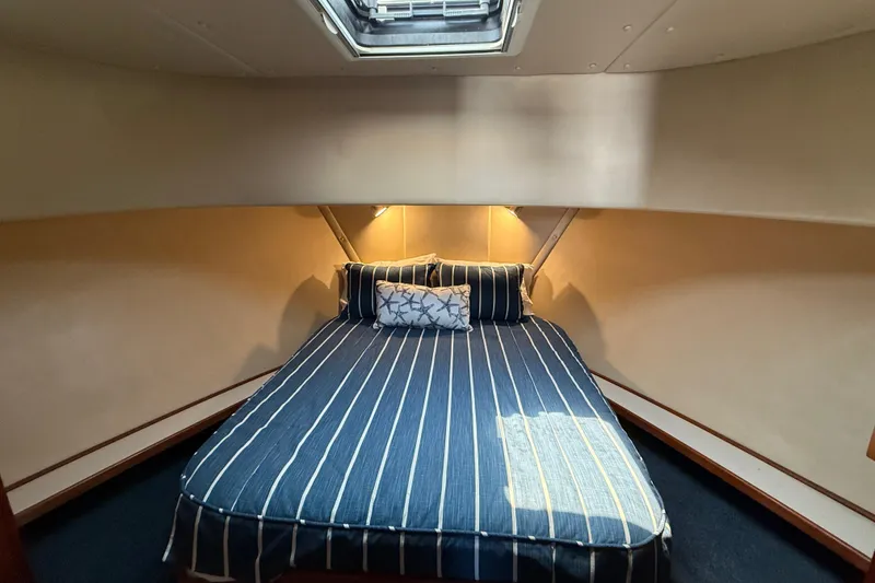 Slide: The Image of Cozy cabin interior of a 2000 Nordic Tug 37 with striped bedding and overhead lighting. - 43
