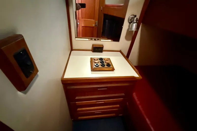 Slide: The Image of Interior of 2000 Nordic Tug 37, featuring a wooden dresser and mirror in a cozy cabin. - 80