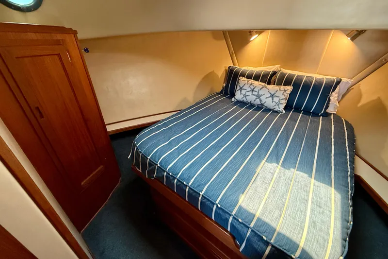 Slide: The Image of Cozy cabin interior of 2000 Nordic Tug 37 with striped bedding and wooden cabinetry. - 45