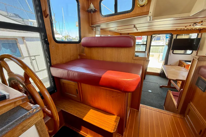Slide: The Image of Interior of a 2000 Nordic Tug 37, featuring wooden helm and red seating. - 56