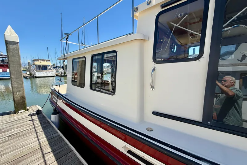 Slide: The Image of 2000 Nordic Tug 37 docked at marina, showcasing side view and windows. - 79