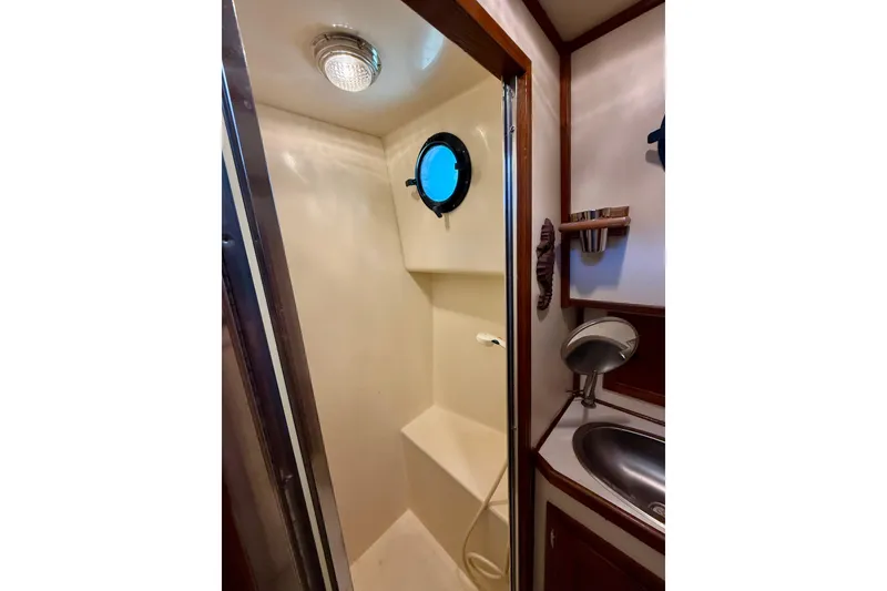 Slide: The Image of Shower area in a 2000 Nordic Tug 37 boat with porthole and sink. - 51