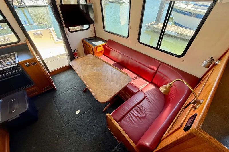 Slide: The Image of Interior of a 2000 Nordic Tug 37 with red leather seating and wooden table. - 55
