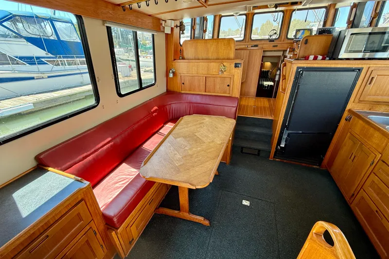 Slide: The Image of Interior of a 2000 Nordic Tug 37 with red seating and wooden cabinetry. - 13
