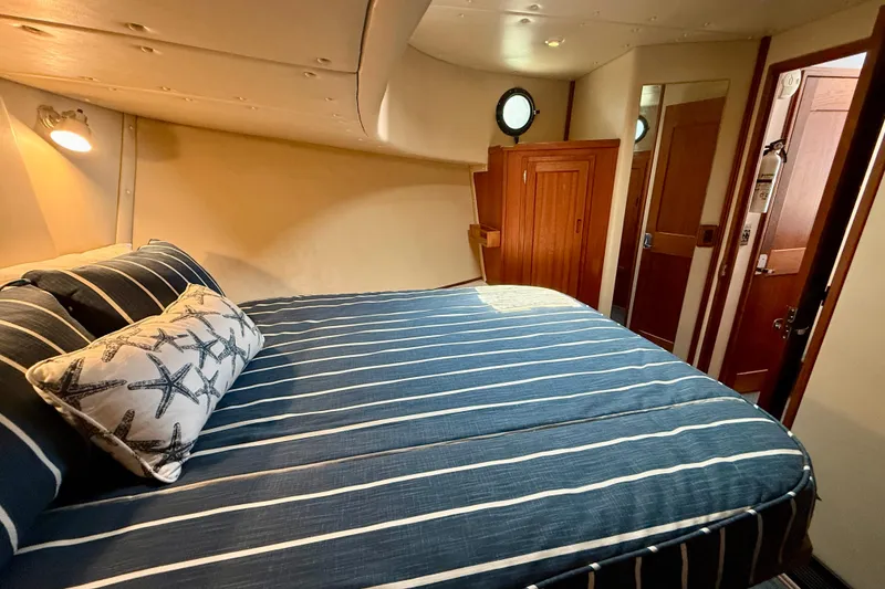 Slide: The Image of Cozy bedroom in a 2000 Nordic Tug 37 boat with striped bedding and wooden accents. - 46