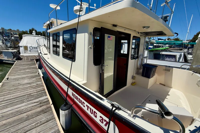 Slide: The Image of 2000 Nordic Tug 37 docked at marina, showcasing exterior and deck area. - 74