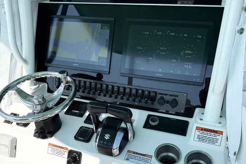 Slide: The Image of 2023 Twin Vee 260 GFX CC boat dashboard with Garmin displays and controls. - 13
