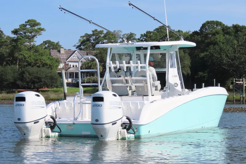 Slide: The Image of 2023 Twin Vee 260 GFX CC boat with dual Suzuki engines on a serene waterway. - 3
