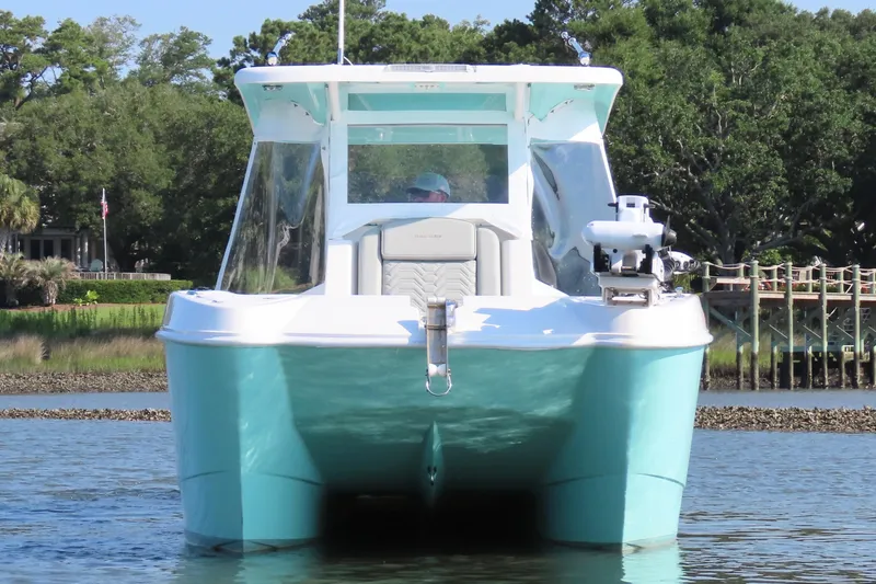 Slide: The Image of 2023 Twin Vee 260 GFX CC boat on water, surrounded by lush greenery. - 5