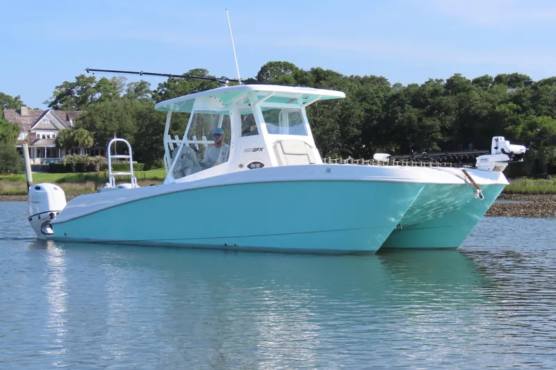 Slide: The Image of 2023 Twin Vee 260 GFX CC boat on calm water, with scenic background. - 6