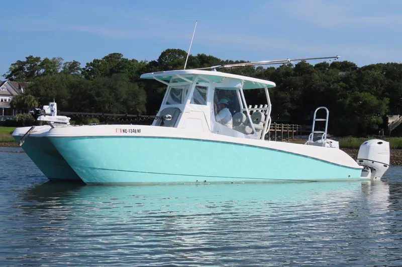 The Image of 2023 Twin Vee 260 GFX CC boat on calm water, featuring a sleek turquoise hull. - 1