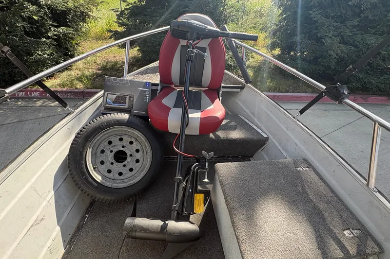 Slide: The Image of 1997 Duroboat 14rlw interior with red seat, spare tire, and fishing equipment. - 10