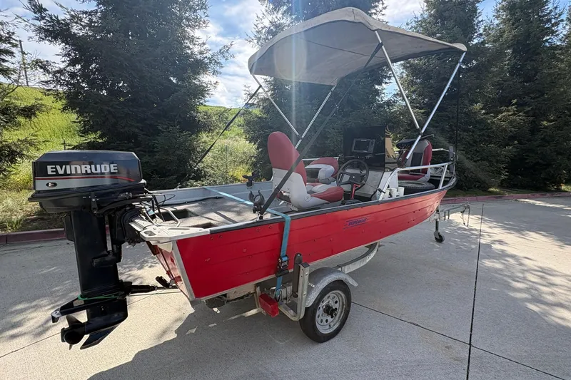 Slide: The Image of 1997 Duroboat 14rlw with Evinrude motor, red exterior, parked on trailer, surrounded by trees. - 5