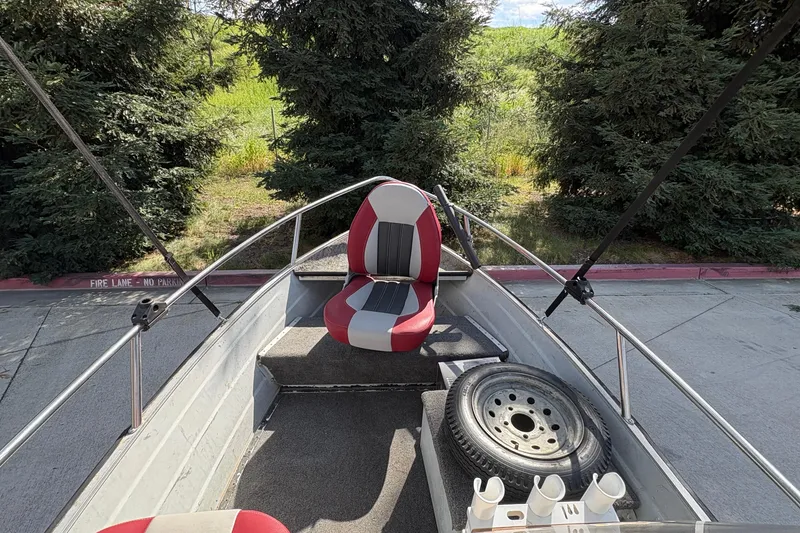 Slide: The Image of 1997 Duroboat 14rlw interior with red and gray seating, spare tire, and lush greenery backdrop. - 11