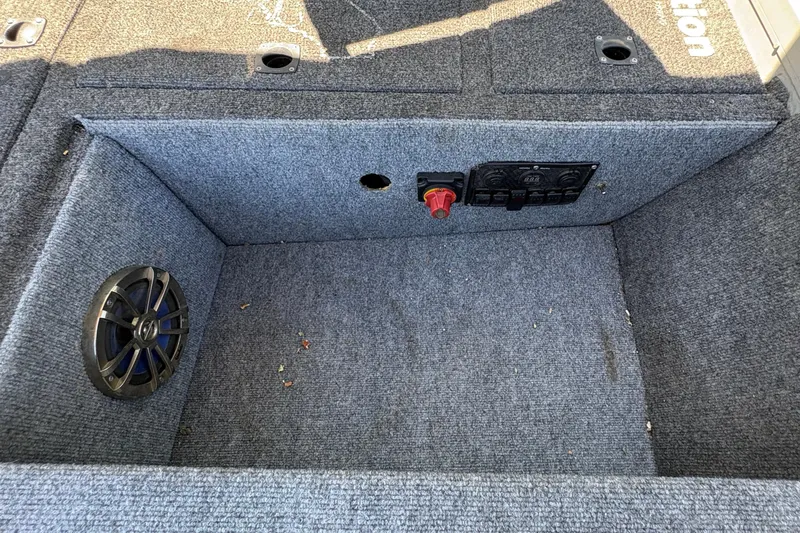 Slide: The Image of Carpeted storage compartment in a 1994 Grumman 1065 boat with speaker and control panel. - 15