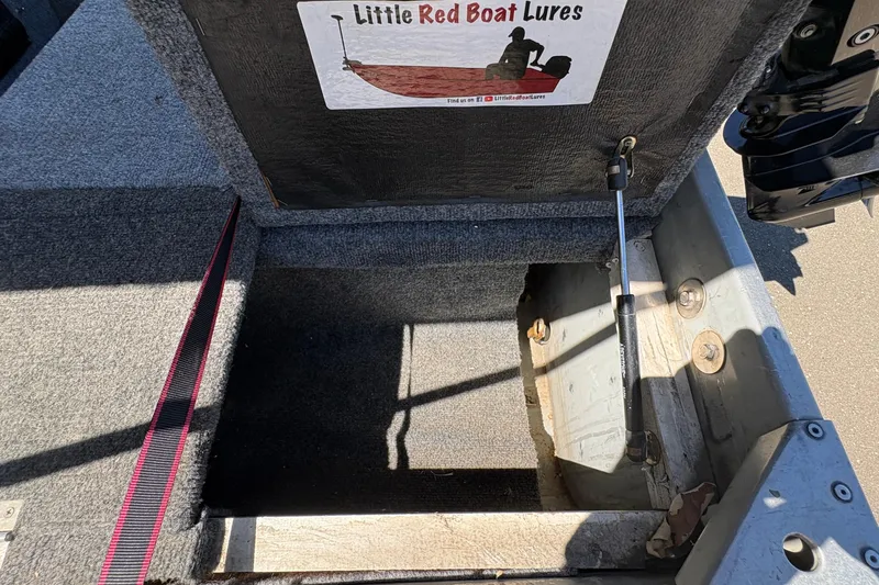 Slide: The Image of Open storage compartment in a 1994 Grumman 1065 boat, featuring "Little Red Boat Lures" sign. - 12