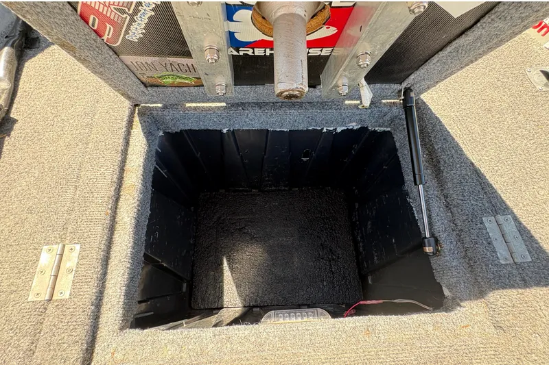 Slide: The Image of Open storage compartment on a 1994 Grumman 1065 boat, featuring carpeted interior and hydraulic lift. - 19
