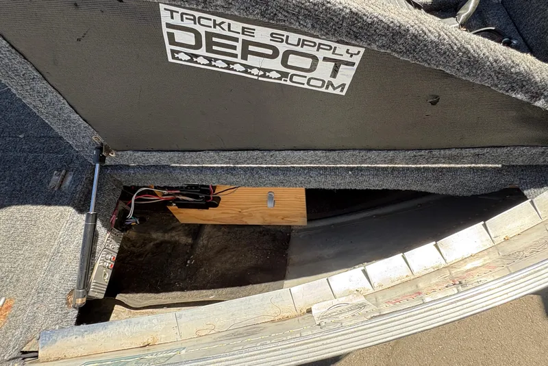 Slide: The Image of Open storage compartment in a 1994 Grumman 1065 boat with Tackle Supply Depot sticker. - 16