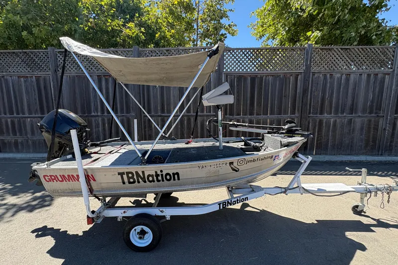 Slide: The Image of 1994 Grumman 1065 boat on trailer with canopy, parked outdoors. - 7