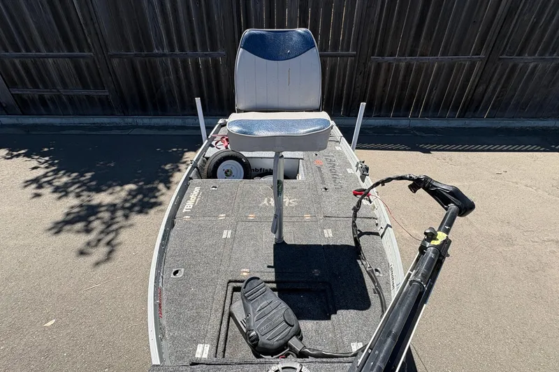 Slide: The Image of 1994 Grumman 1065 boat with seating and trolling motor, parked on pavement. - 4