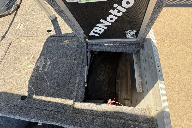 Slide: The Image of Open storage compartment on a 1994 Grumman 1065 boat with carpeted interior. - 23