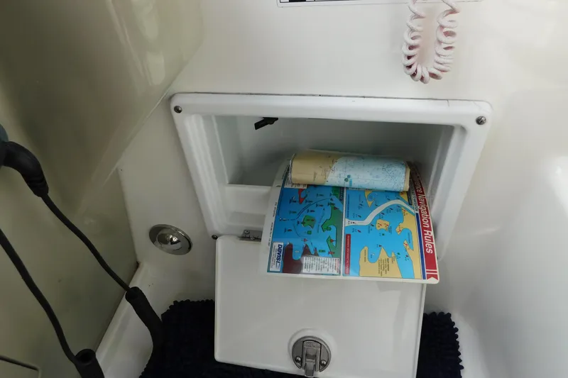 Slide: The Image of Storage compartment with navigation maps on a 2010 Sea Ray Sundancer 260 boat. - 32