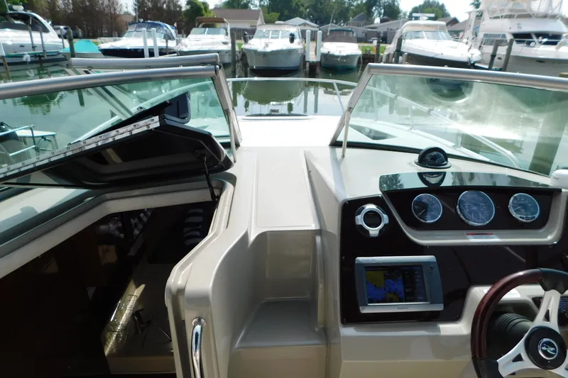 Slide: The Image of Cockpit view of 2010 Sea Ray Sundancer 260 with dashboard and marina background. - 37