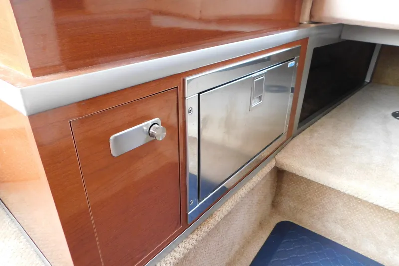Slide: The Image of Interior of 2010 Sea Ray Sundancer 260 showing wooden cabinetry and stainless steel fridge. - 53