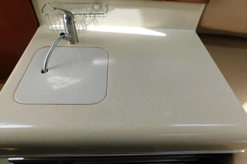 Slide: The Image of Kitchen sink area on a 2010 Sea Ray Sundancer 260 boat, featuring a sleek countertop. - 62