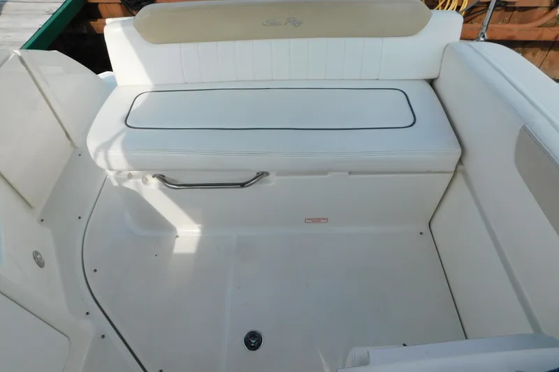 Slide: The Image of 2010 Sea Ray Sundancer 260 boat seating area with white upholstery and storage compartment. - 9