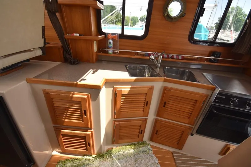Slide: The Image of 2013 Ranger Tugs R-29 boat kitchen with wooden cabinets and dual sinks. - 24