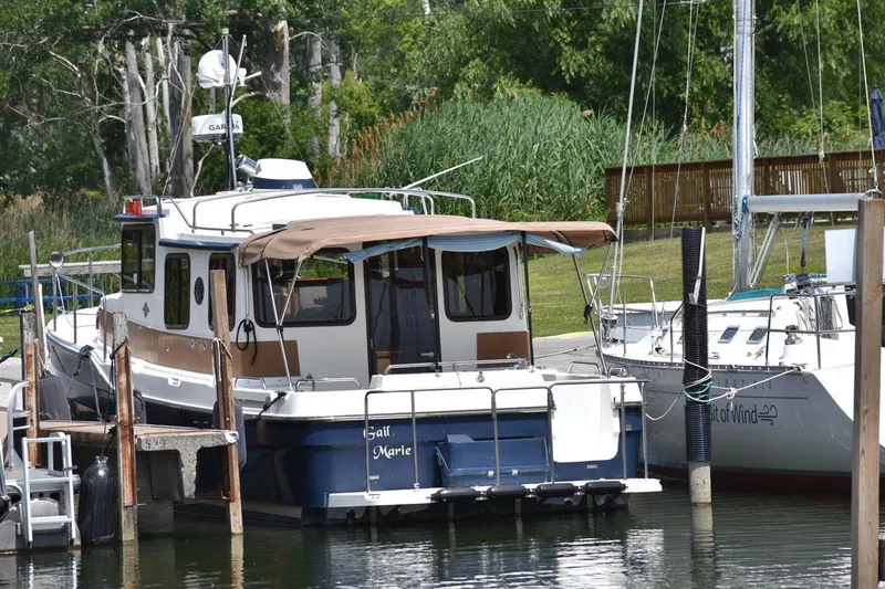 Slide: The Image of 2013 Ranger Tugs R-29 boat docked at a marina, surrounded by lush greenery. - 2