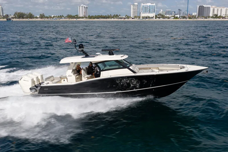 The Image of 2024 Scout 425 LXF boat cruising on ocean near city skyline. - 0