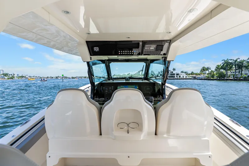 Slide: The Image of 2024 Scout 425 LXF boat interior with helm, overlooking scenic waterfront. - 32