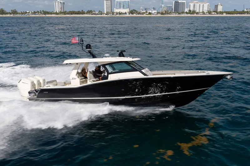 Slide: The Image of 2024 Scout 425 LXF boat cruising on ocean near city skyline. - 1