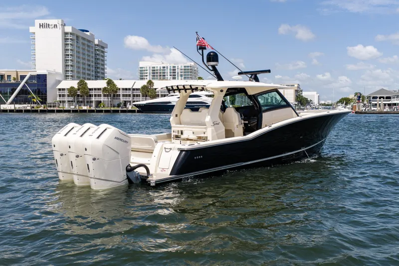 Slide: The Image of 2024 Scout 425 LXF boat with triple Mercury engines on urban waterfront. - 8