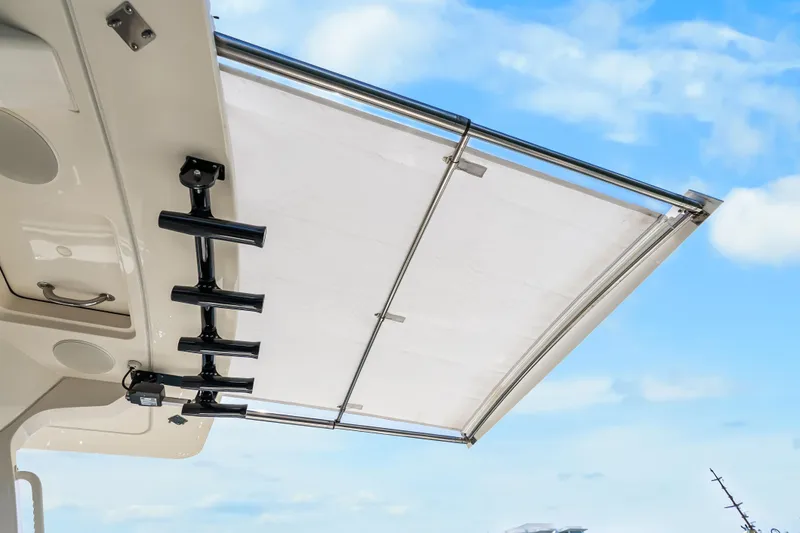 Slide: The Image of 2024 Scout 425 LXF boat with retractable sunshade and rod holders against blue sky. - 39