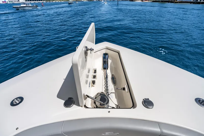 Slide: The Image of Bow of 2024 Scout 425 LXF boat with anchor compartment open on blue water. - 25