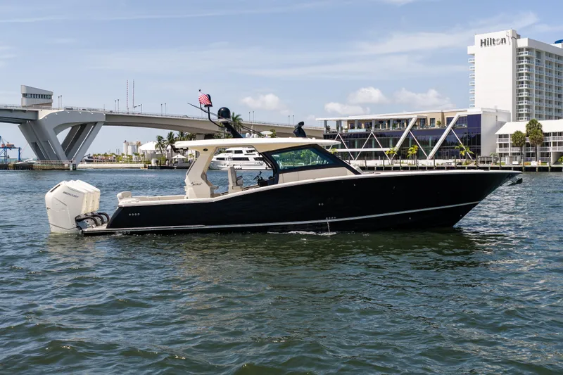 Slide: The Image of 2024 Scout 425 LXF luxury boat cruising near a bridge and waterfront buildings. - 9