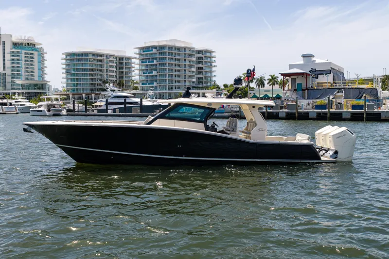 Slide: The Image of 2024 Scout 425 LXF luxury boat docked in marina, modern buildings in background. - 16