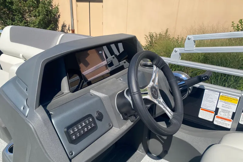 Slide: The Image of 2026 Sun Tracker Fishin' Barge 22 DLX dashboard with steering wheel and control panel. - 100