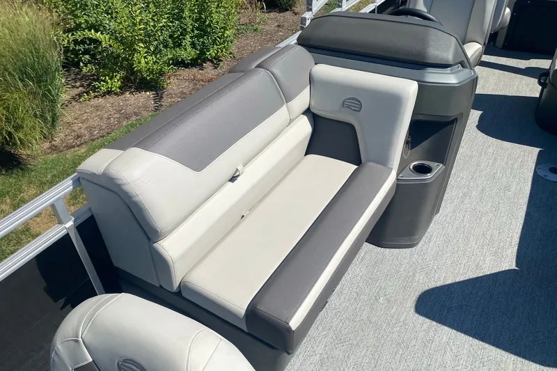 Slide: The Image of 2026 Sun Tracker Fishin' Barge 22 DLX interior seating with cup holder, outdoor setting. - 6
