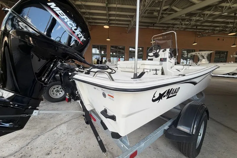 Slide: The Image of 2026 Mako Pro Skiff 15 CC boat on trailer with Mercury engine in a warehouse. - 2
