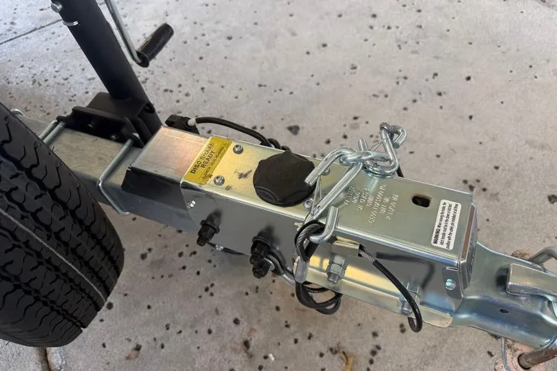 Slide: The Image of Trailer hitch of 2026 Mako Pro Skiff 15 CC, featuring safety chains and tire. - 5