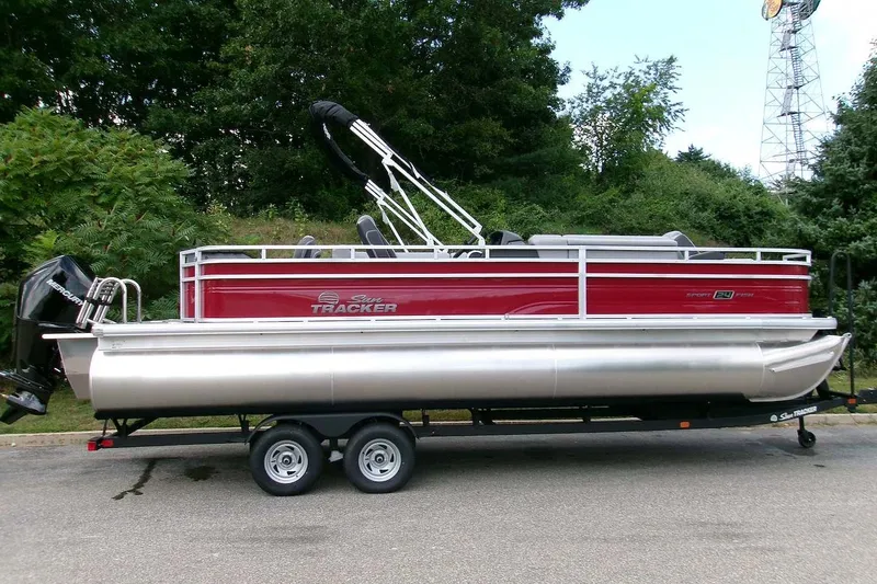 The Image of 2026 Sun Tracker Sportfish 24 XP3 pontoon boat on trailer, red and silver design. - 0