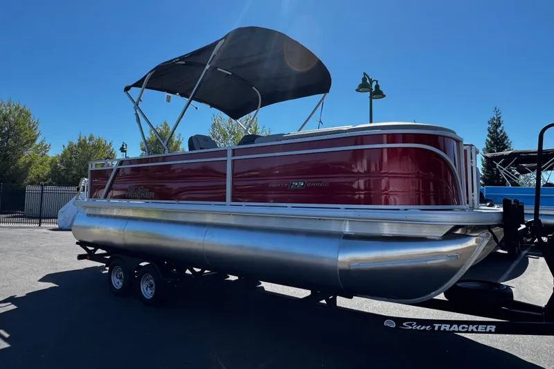 Slide: The Image of 2026 Sun Tracker Party Barge 22 RF XP3 pontoon boat on trailer, parked outdoors. - 3