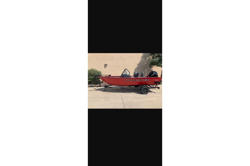 Slide: The Image of 2026 Tracker Pro Guide V-16 WT boat in vibrant red, parked outdoors. - 13